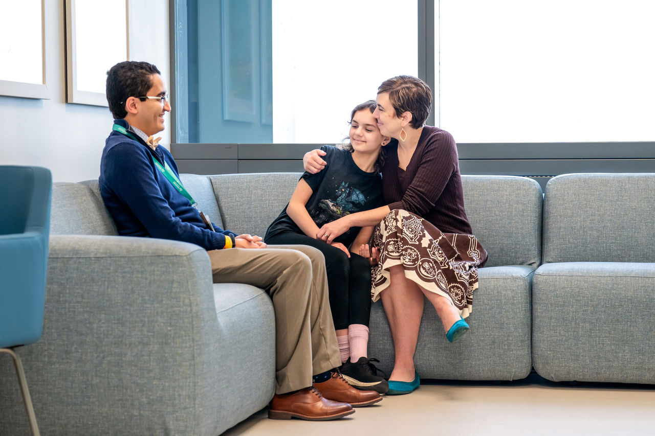 A doctor speaking to a mother and child on a couch