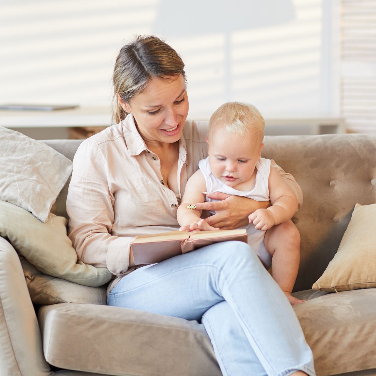 Mother sitting on the couch reading to her infant.