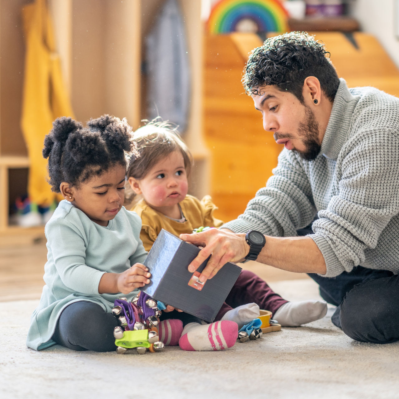A teacher reading to two toddlers.