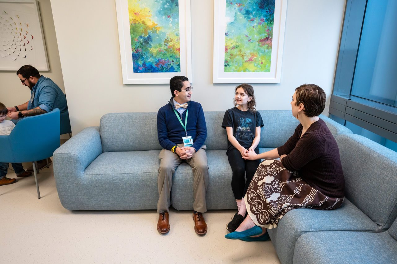 Mother and child speaking with a health care professional in a waiting area