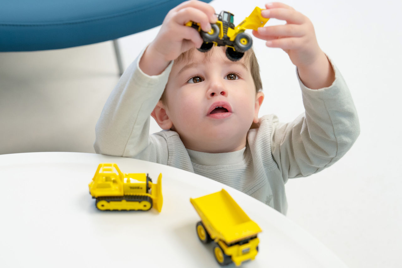 A young boy playing with toy trucks on a table