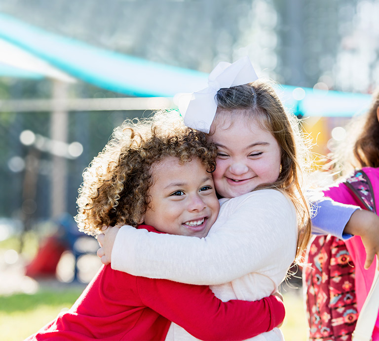 Two girls hugging, one is special needs