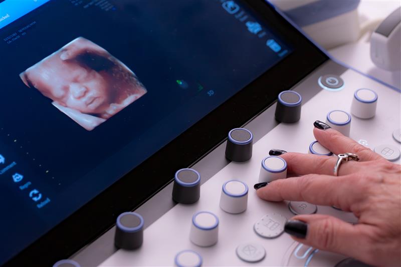 Ultrasound technician operating 3D fetal imaging machine