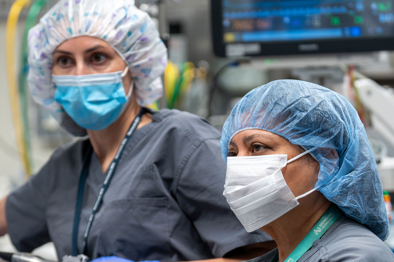Medical staff in surgical attire monitor patient vitals