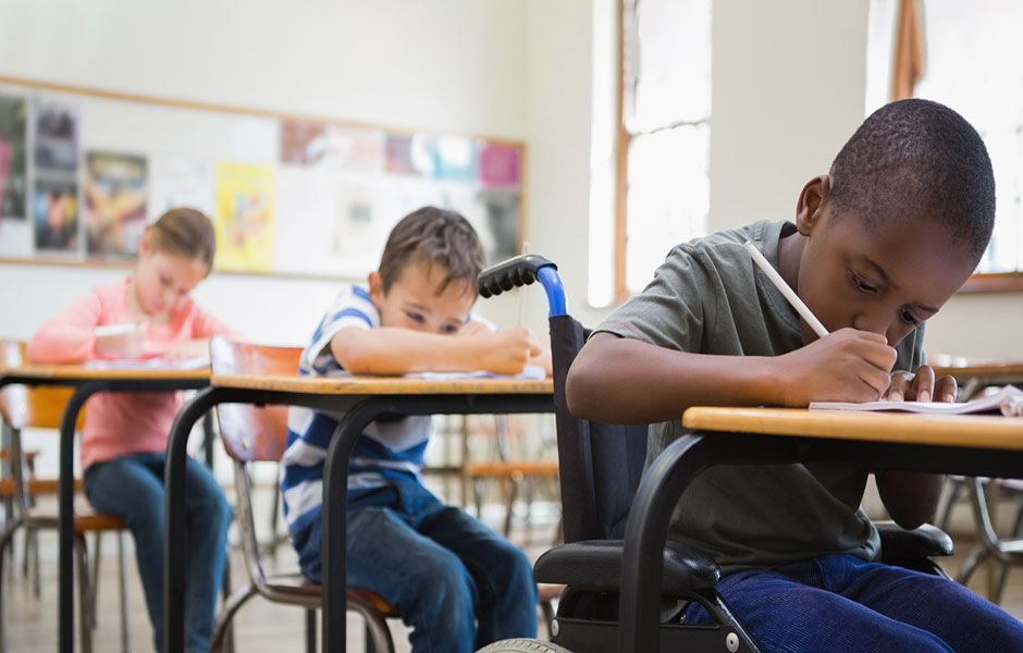 Three school-aged children studying at school desk